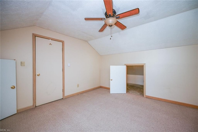 bonus room featuring lofted ceiling, ceiling fan, light carpet, and a textured ceiling