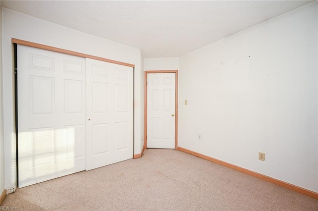 unfurnished bedroom with light carpet and a closet