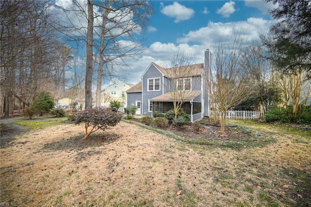 back of house featuring a lawn and a sunroom