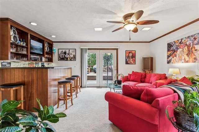 living room featuring ceiling fan, ornamental molding, light colored carpet, french doors, and indoor bar