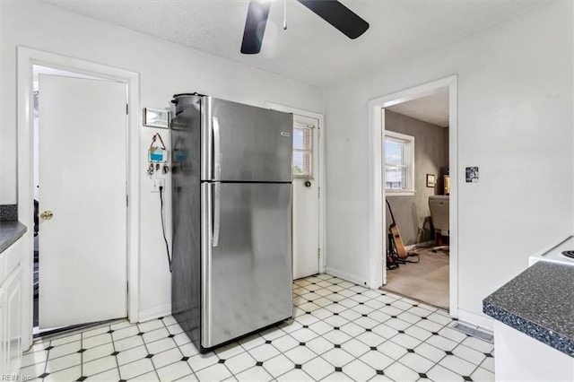 kitchen with ceiling fan, stainless steel fridge, and white cabinets
