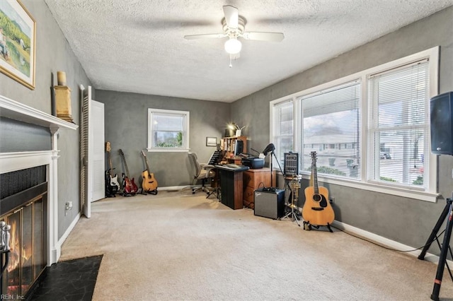 misc room featuring ceiling fan, a tiled fireplace, carpet floors, and a textured ceiling