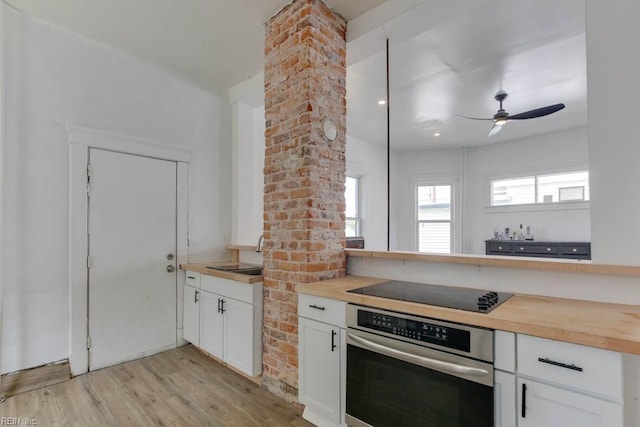 kitchen with stainless steel oven, black electric stovetop, wooden counters, and white cabinets