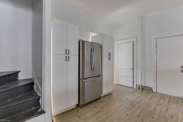 kitchen with stainless steel fridge, light hardwood / wood-style floors, and white cabinets