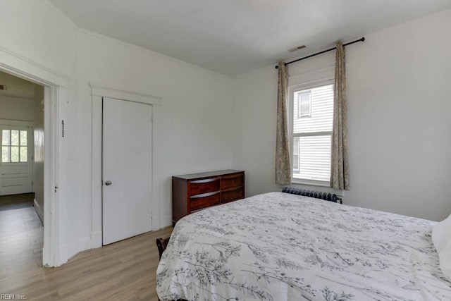 bedroom featuring multiple windows, light hardwood / wood-style floors, and a closet