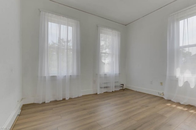 spare room featuring a healthy amount of sunlight and light wood-type flooring