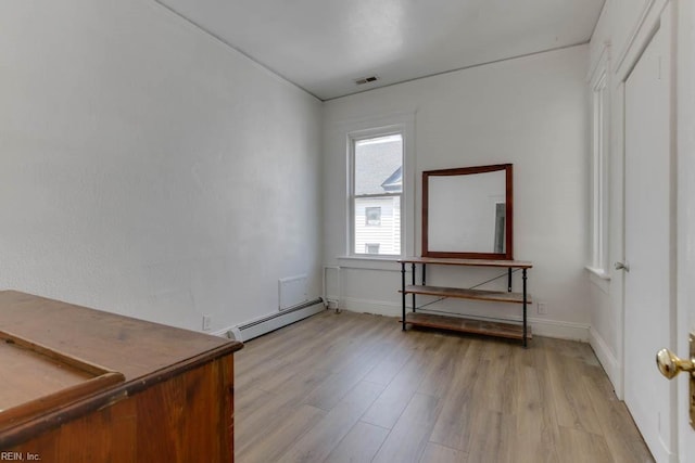 unfurnished room with a baseboard heating unit and light hardwood / wood-style flooring