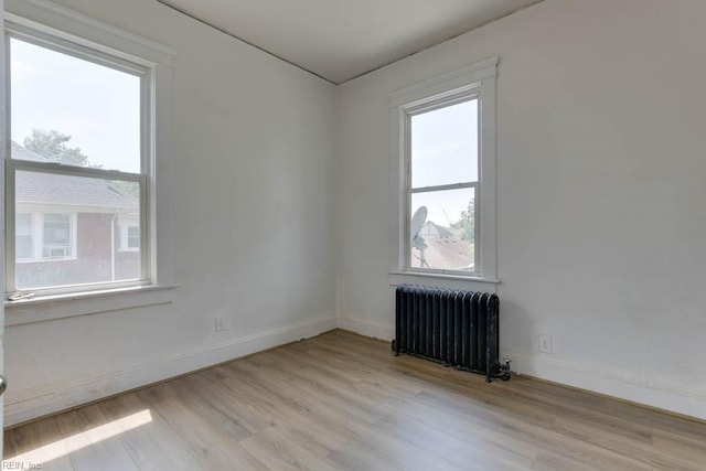 unfurnished room featuring radiator and light hardwood / wood-style flooring