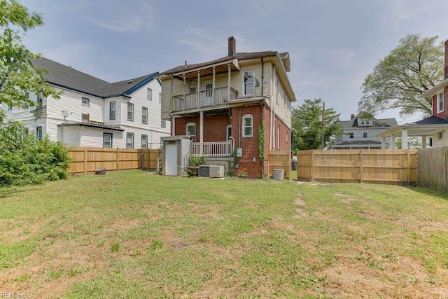 rear view of property with a yard, a balcony, and central air condition unit