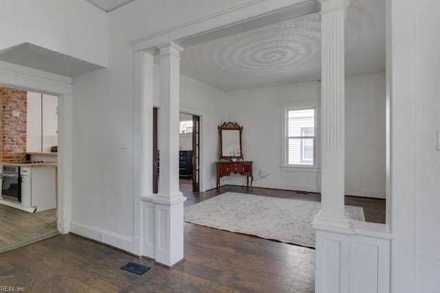 corridor with dark wood-type flooring and decorative columns