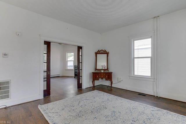 spare room with a baseboard heating unit and dark hardwood / wood-style floors