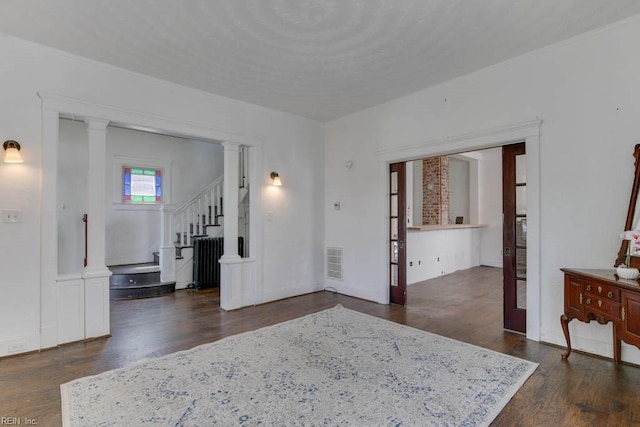 interior space with dark hardwood / wood-style flooring and decorative columns