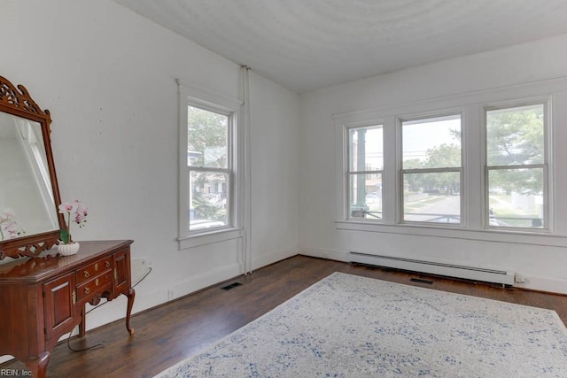 spare room featuring a baseboard heating unit and dark hardwood / wood-style floors