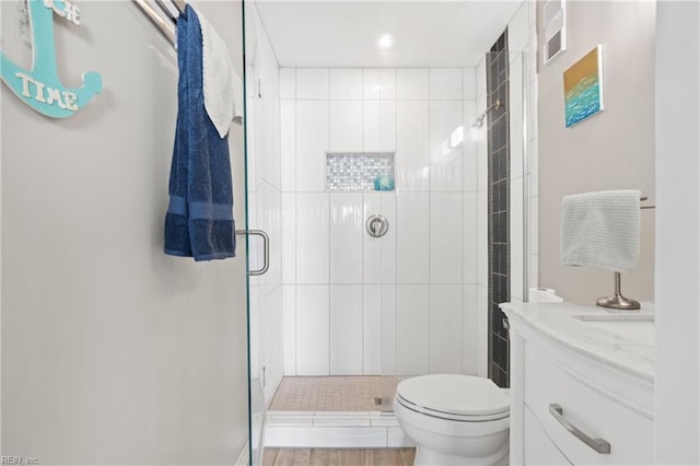 bathroom with toilet, vanity, and a shower with shower door