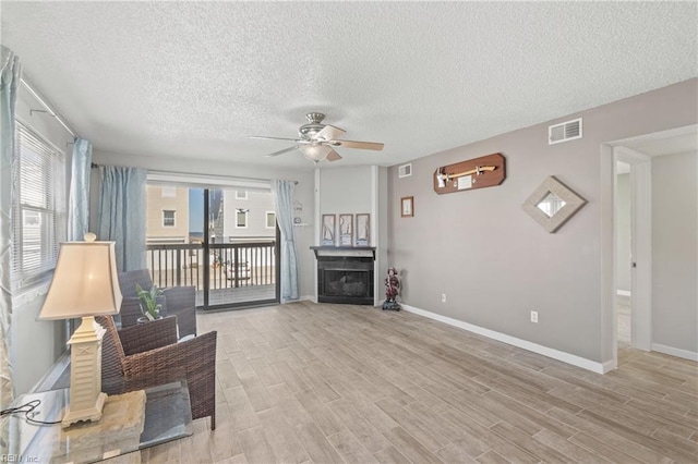 living room featuring a textured ceiling, ceiling fan, and light hardwood / wood-style flooring