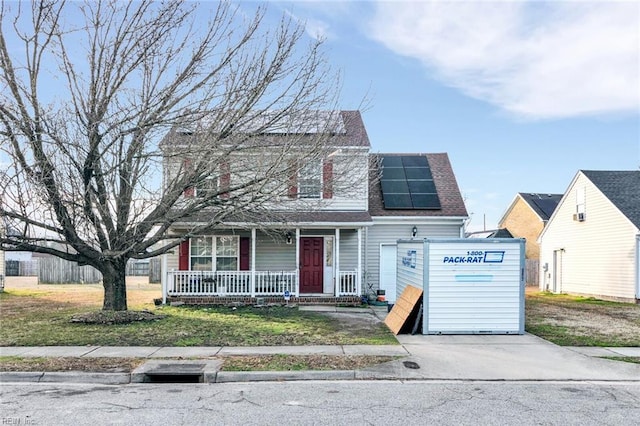 view of front facade featuring a porch, a front yard, and solar panels