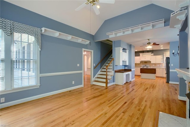 unfurnished living room featuring vaulted ceiling, ceiling fan, and light hardwood / wood-style flooring