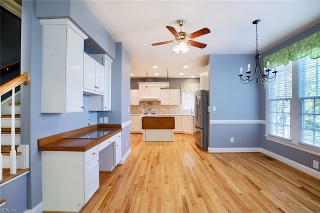 kitchen featuring white cabinetry, plenty of natural light, pendant lighting, and stainless steel refrigerator