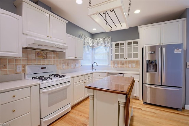 kitchen featuring a kitchen island, appliances with stainless steel finishes, white cabinets, and light hardwood / wood-style floors