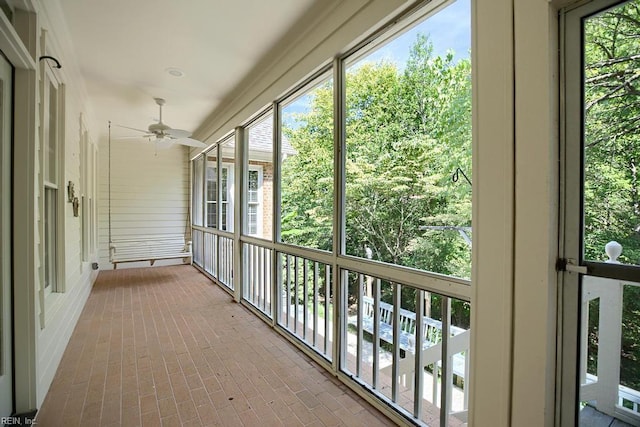 unfurnished sunroom featuring ceiling fan