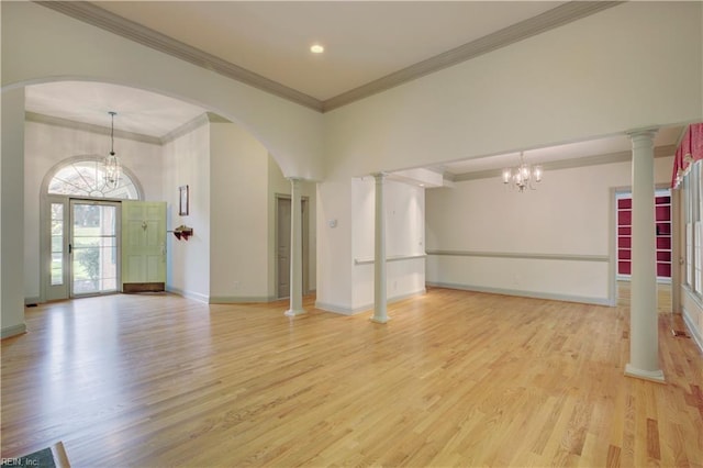 spare room featuring an inviting chandelier, ornamental molding, light hardwood / wood-style flooring, and decorative columns