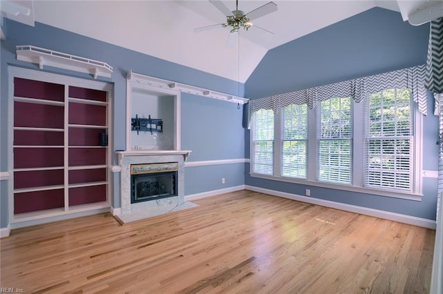 unfurnished living room featuring hardwood / wood-style flooring, vaulted ceiling, a premium fireplace, and ceiling fan