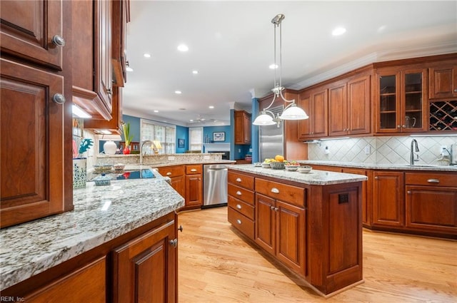 kitchen with a kitchen island, glass insert cabinets, decorative light fixtures, stainless steel dishwasher, and a sink