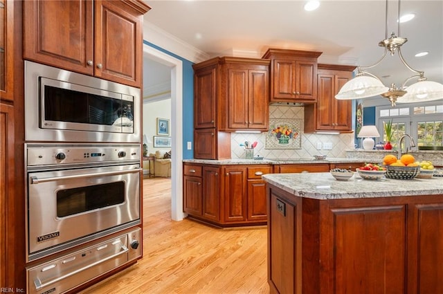 kitchen with light stone counters, hanging light fixtures, ornamental molding, backsplash, and a warming drawer