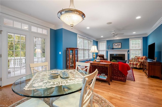 dining area featuring light wood-type flooring, a premium fireplace, crown molding, and recessed lighting