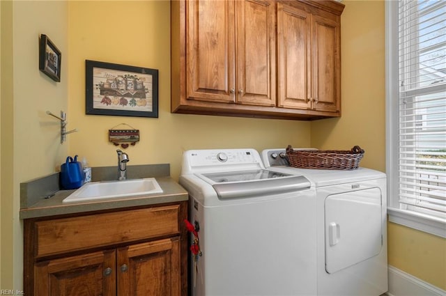 washroom with washing machine and dryer, a sink, and cabinet space