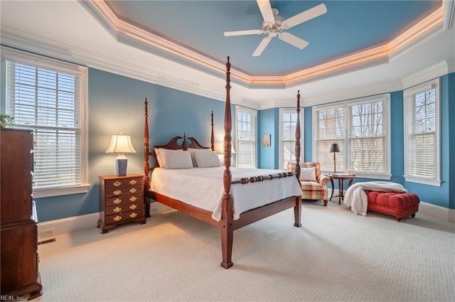 carpeted bedroom with baseboards, a tray ceiling, ceiling fan, and crown molding