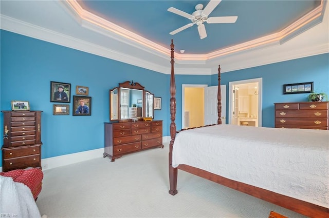 carpeted bedroom featuring ceiling fan, ensuite bathroom, baseboards, ornamental molding, and a tray ceiling