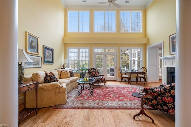 living area with a wealth of natural light, a fireplace, crown molding, and wood finished floors