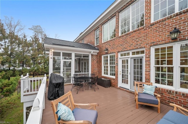 wooden deck featuring outdoor dining space and a sunroom