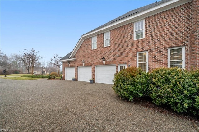 view of home's exterior with driveway, brick siding, and an attached garage