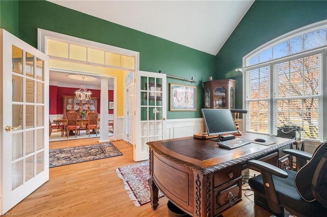 office area featuring vaulted ceiling, french doors, light wood-type flooring, wainscoting, and an inviting chandelier