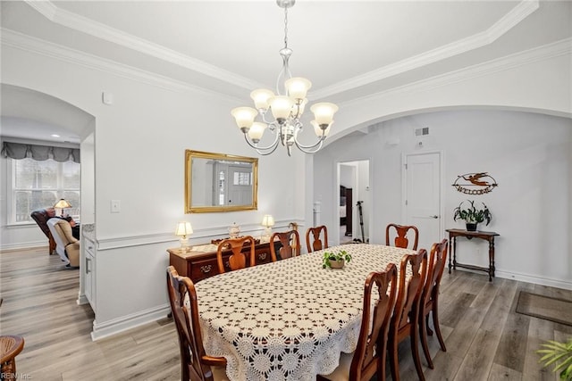 dining space featuring crown molding, a notable chandelier, and light wood-type flooring