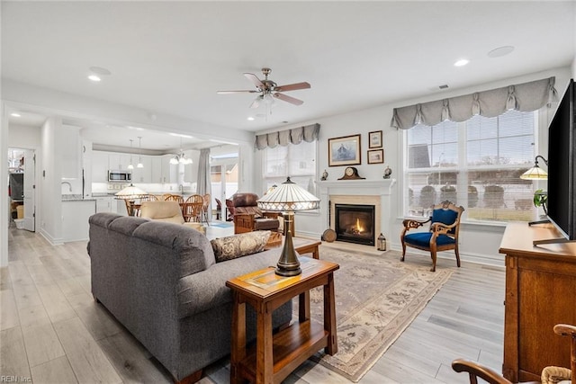 living room with ceiling fan with notable chandelier and light hardwood / wood-style floors