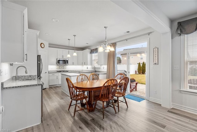 dining area with a chandelier, light hardwood / wood-style floors, and sink