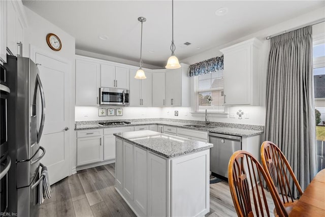 kitchen featuring sink, hanging light fixtures, a kitchen island, stainless steel appliances, and white cabinets