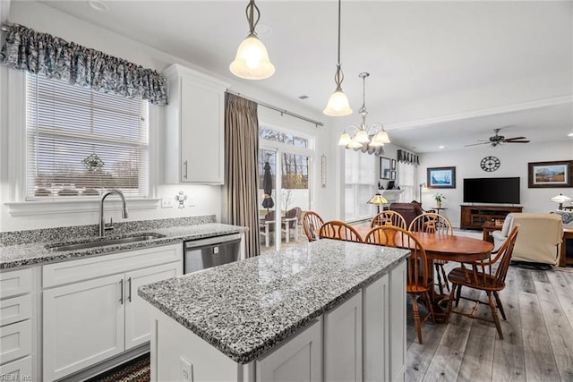 kitchen featuring sink, dishwasher, a kitchen island, pendant lighting, and white cabinets