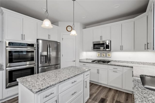 kitchen with dark hardwood / wood-style flooring, pendant lighting, stainless steel appliances, light stone countertops, and white cabinets