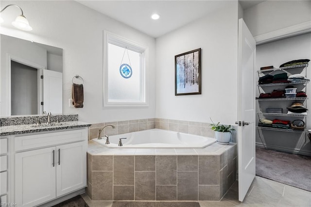 bathroom featuring tile patterned floors, vanity, and tiled tub