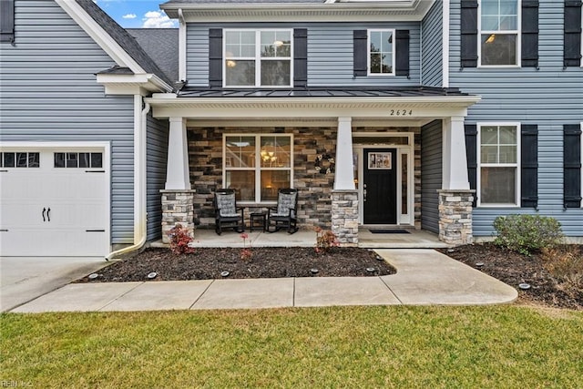 entrance to property featuring a garage, a lawn, and covered porch