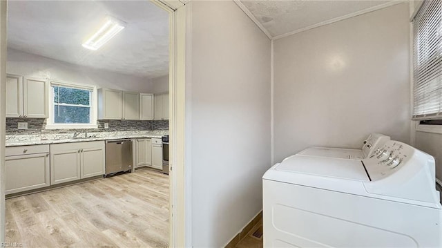 laundry area with washer and dryer, sink, and light wood-type flooring