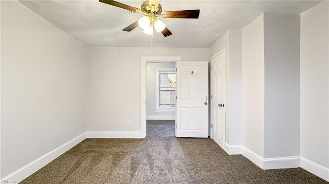 spare room featuring dark carpet and ceiling fan