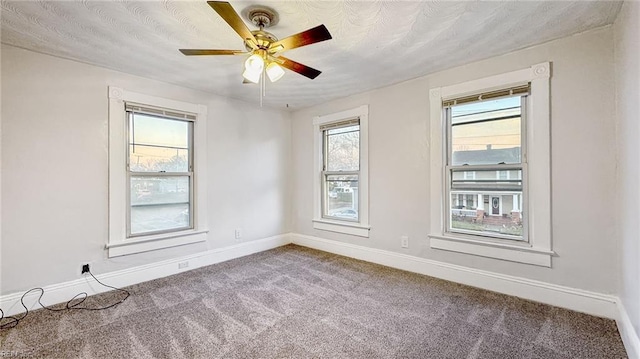 empty room featuring a wealth of natural light, ceiling fan, and carpet flooring