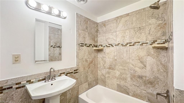 bathroom featuring washtub / shower combination, sink, and tile walls