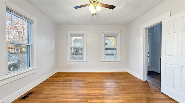 empty room featuring ceiling fan, light hardwood / wood-style flooring, and a textured ceiling