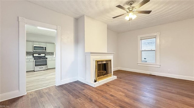 unfurnished living room with wood-type flooring and ceiling fan